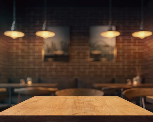 Empty tabletop in the coffe shop at night over defocused background with copy space