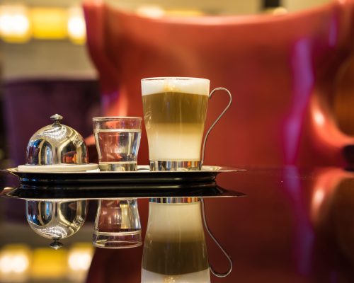 Glass of latte Coffee cup and syrup on the table in lounge bar background.